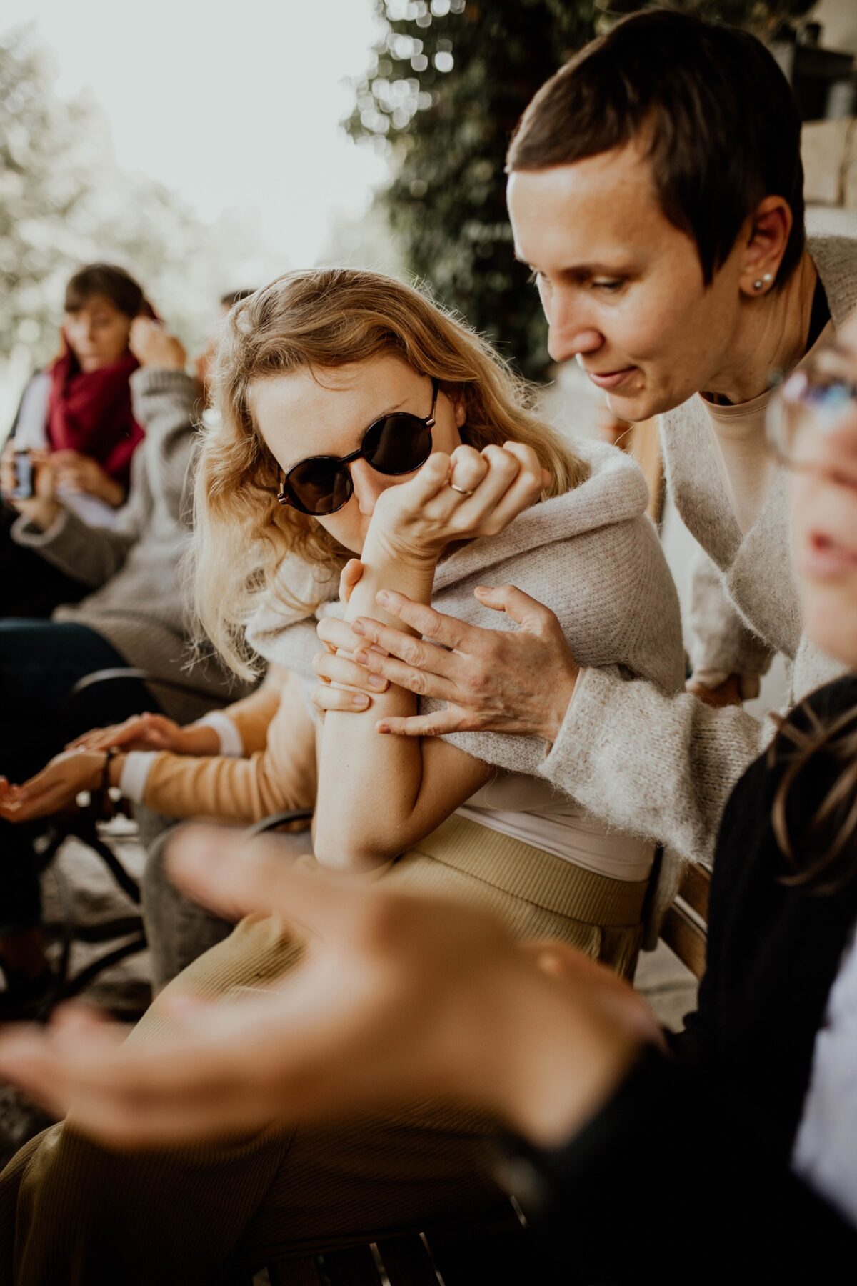Kobieta w okularach wącha nadgarstek, testując olejek eteryczny - warsztaty perfumiarskie w warszawie