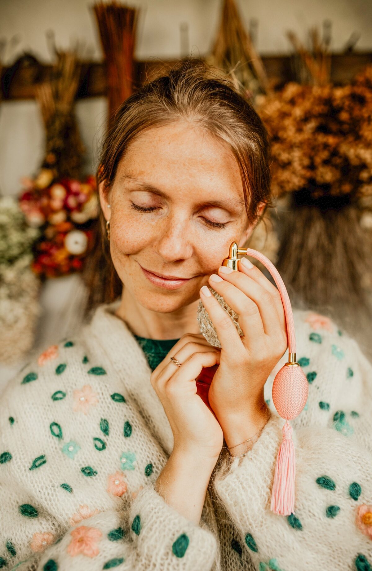 uczestniczka warsztatu tworzenia perfum olejkowej szkoły z zamkniętymi oczami trzyma flakon z perfumami