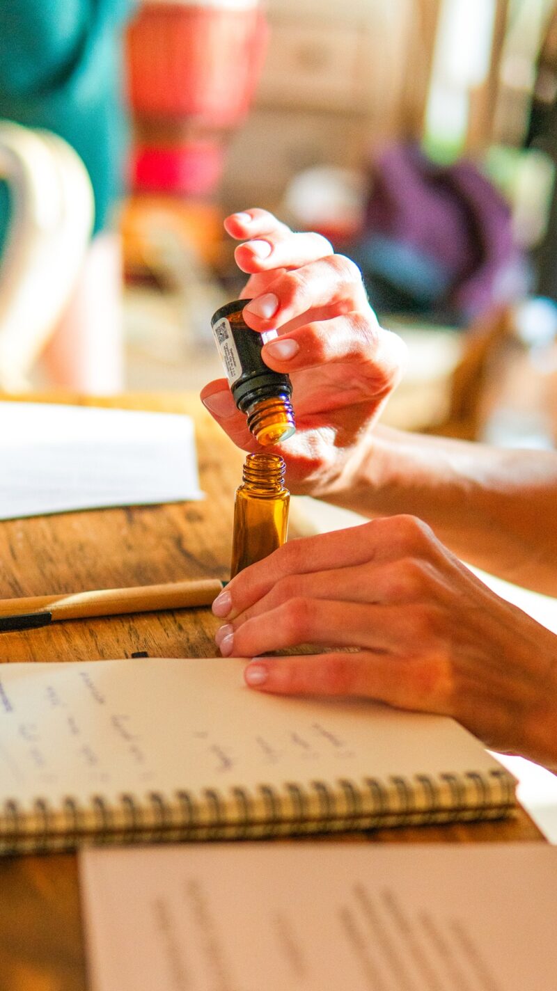 Ręce napełniające fiolkę olejkiem podczas praktycznych warsztatów aromaterapii