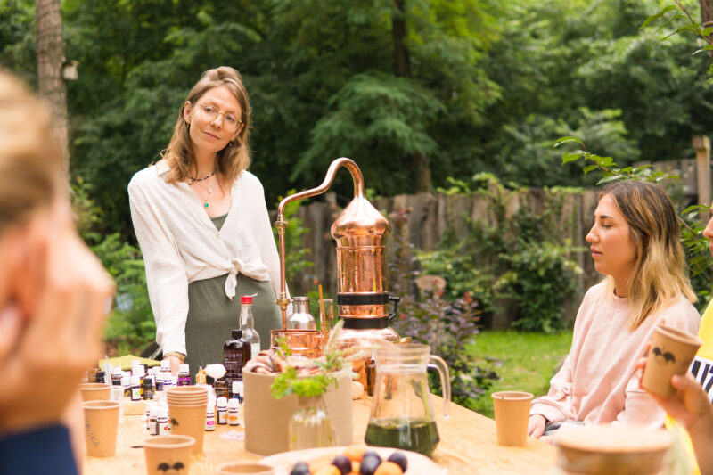 Kobieta prowadząca warsztaty aromaterapii z destylatorem i naturalnymi olejkami