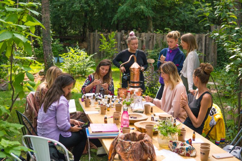 Uczestnicy warsztatu aromaterapii wokół stołu z destylatorem i olejkami eterycznymi