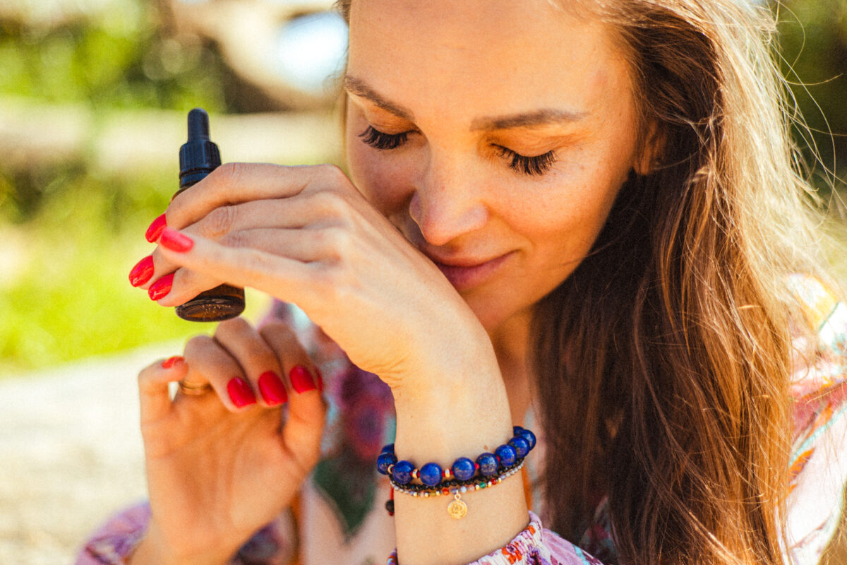 kobieta zbliża dłoń do nosa, testując zapach kompozycji - warsztaty perfumiarskie olejkowej szkoły