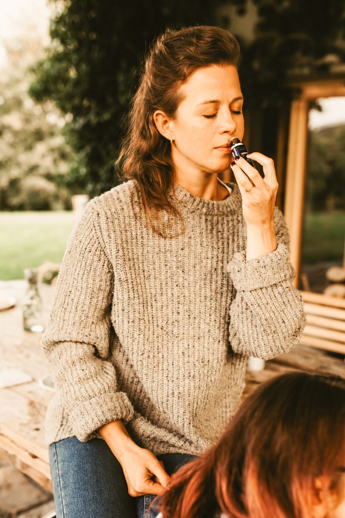 kobieta w swetrze bada zapach olejku eteryczneg na warsztatach tworzenia perfum