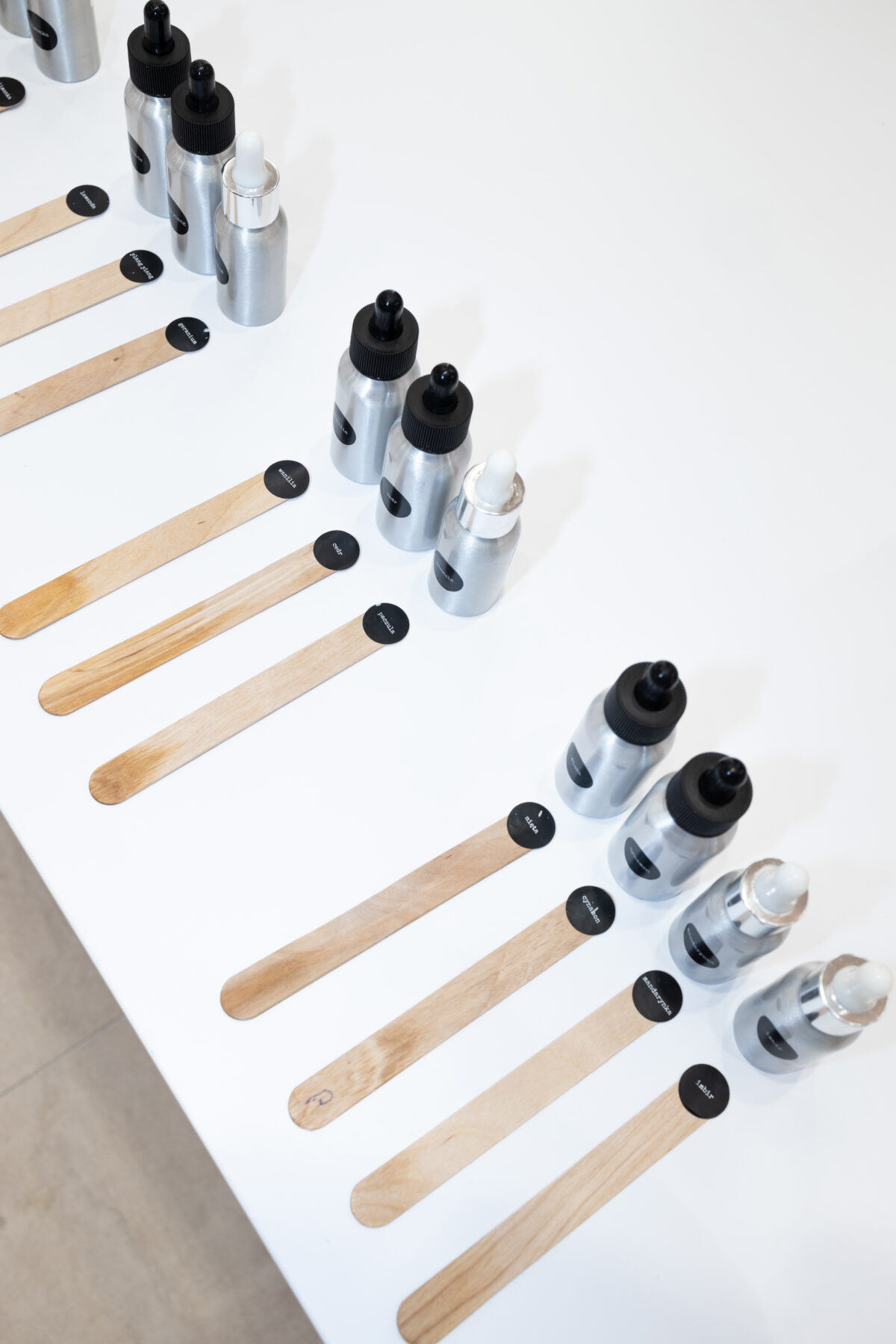 Zestaw butelek i drewnianych pałeczek do testowania zapachów – strefa doświadczenia.